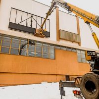 Работы по монтажу на стене цеха завода при помощи автовышки